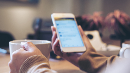 hands holding a mug and a mobile phone