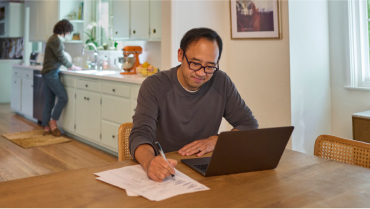 man sitting on a couch and looking at a laptop